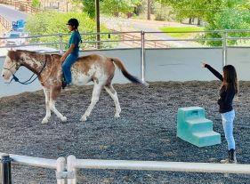 photo of woman on horse with another woman coaching